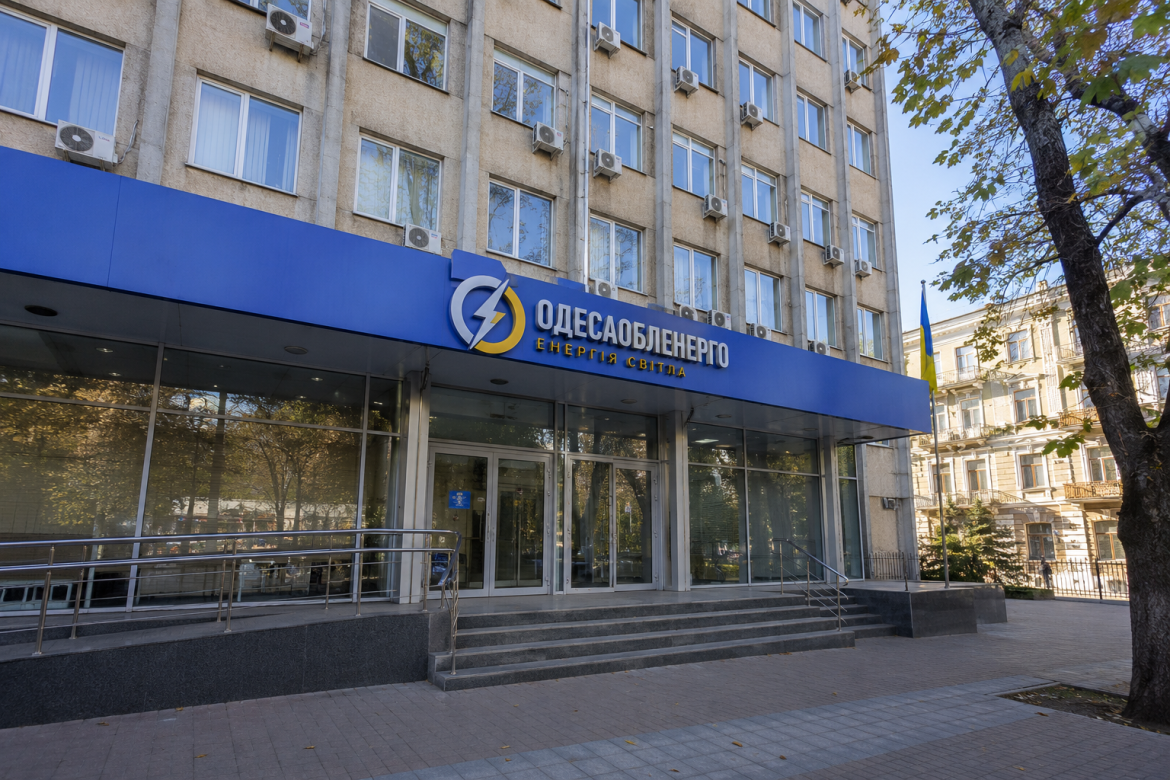 Фасад головного офісу Одесаобленерго з логотипом компанії та українським прапором поруч із входом